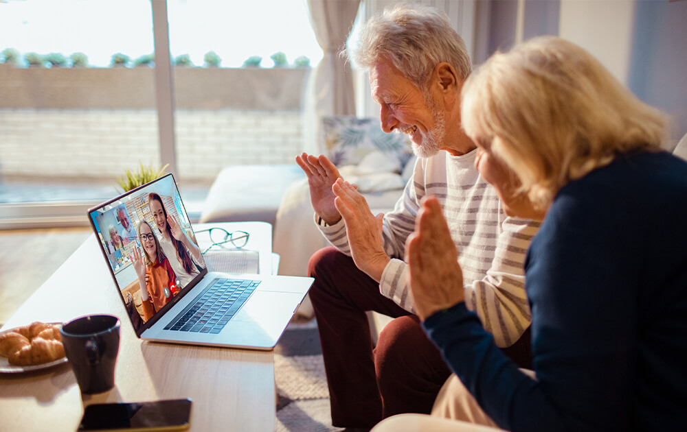 Older couple sitting together, video chatting with daughter and grandchild on laptop.
